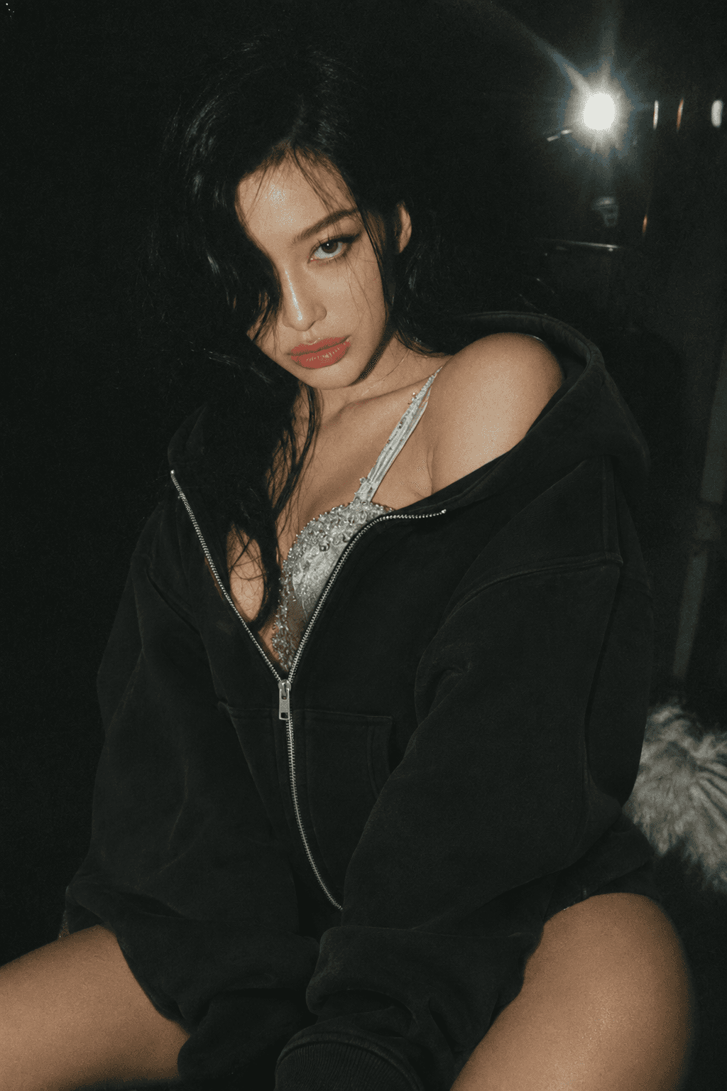 Editorial shot from the store: a model in a black zip hoodie, low light